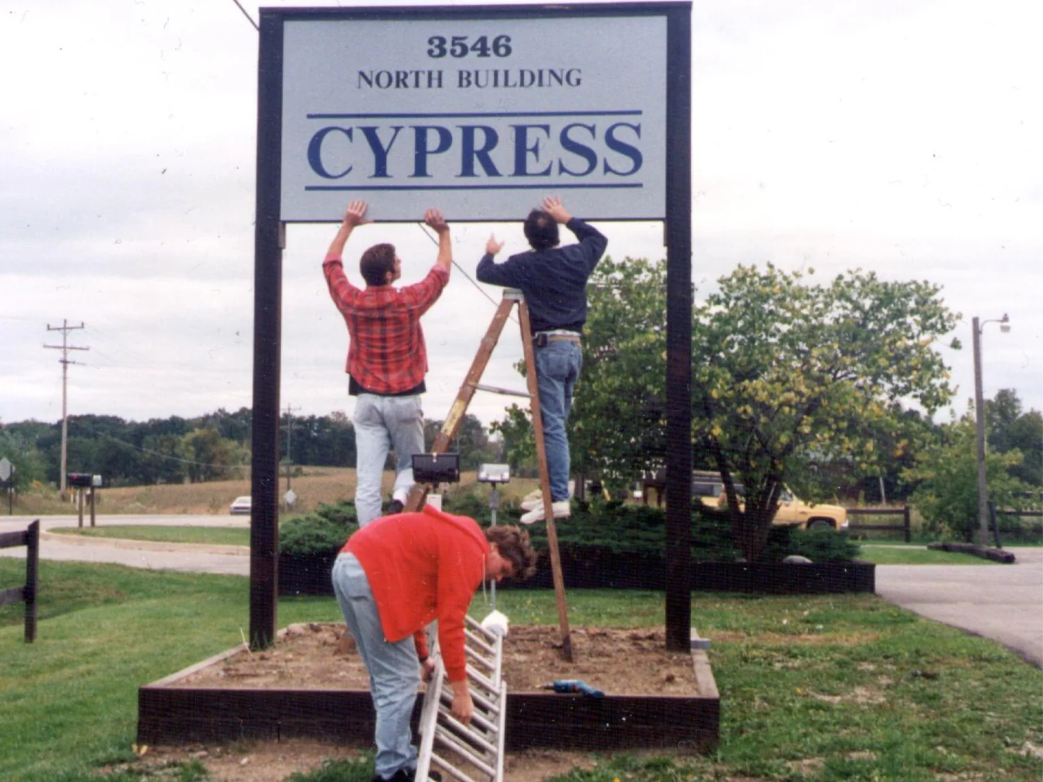 Cypress employees installing the company sign at the Metamora, Michigan building in 1994