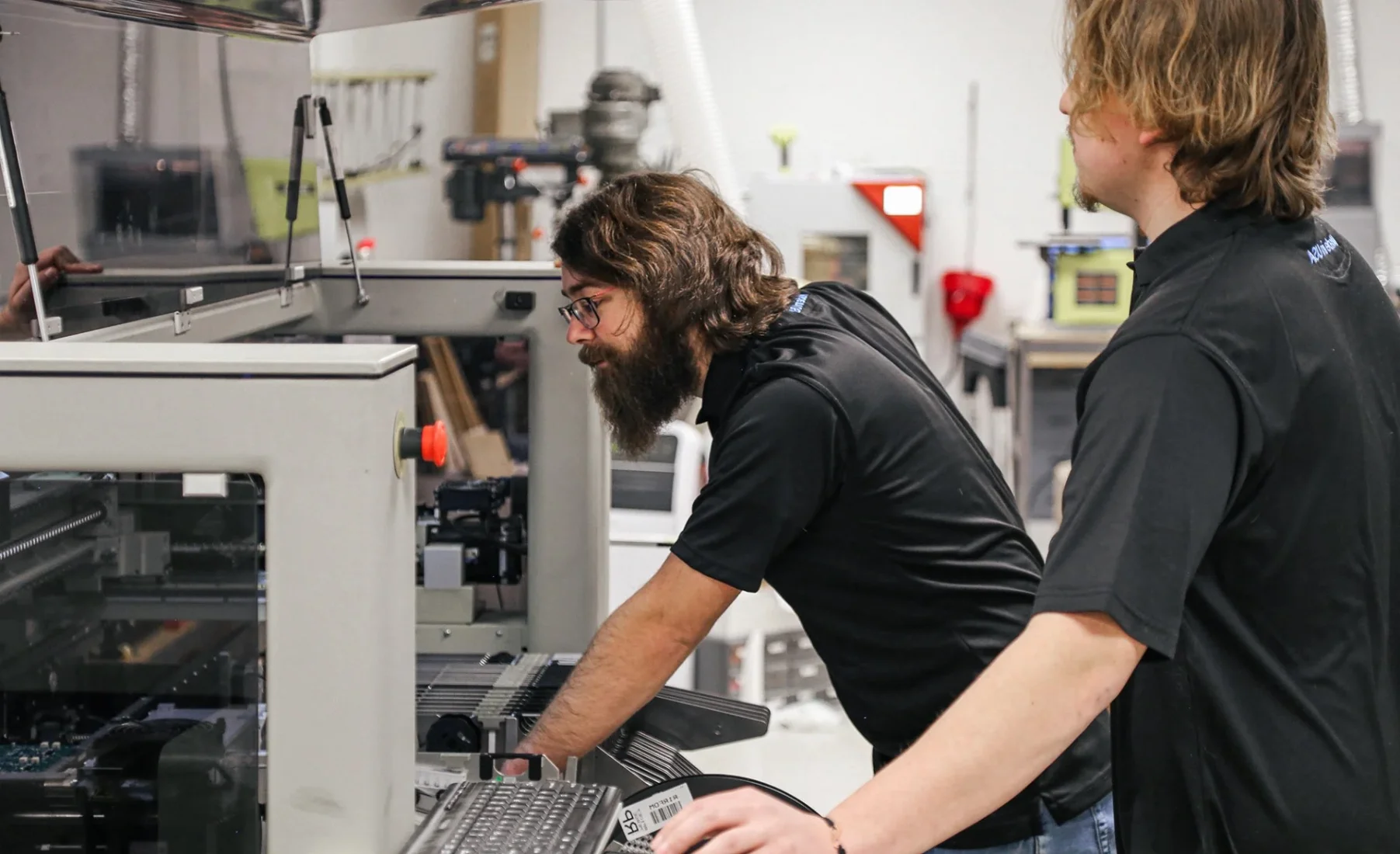 Cypress technicians operating electronics manufacturing equipment in the Lapeer facility