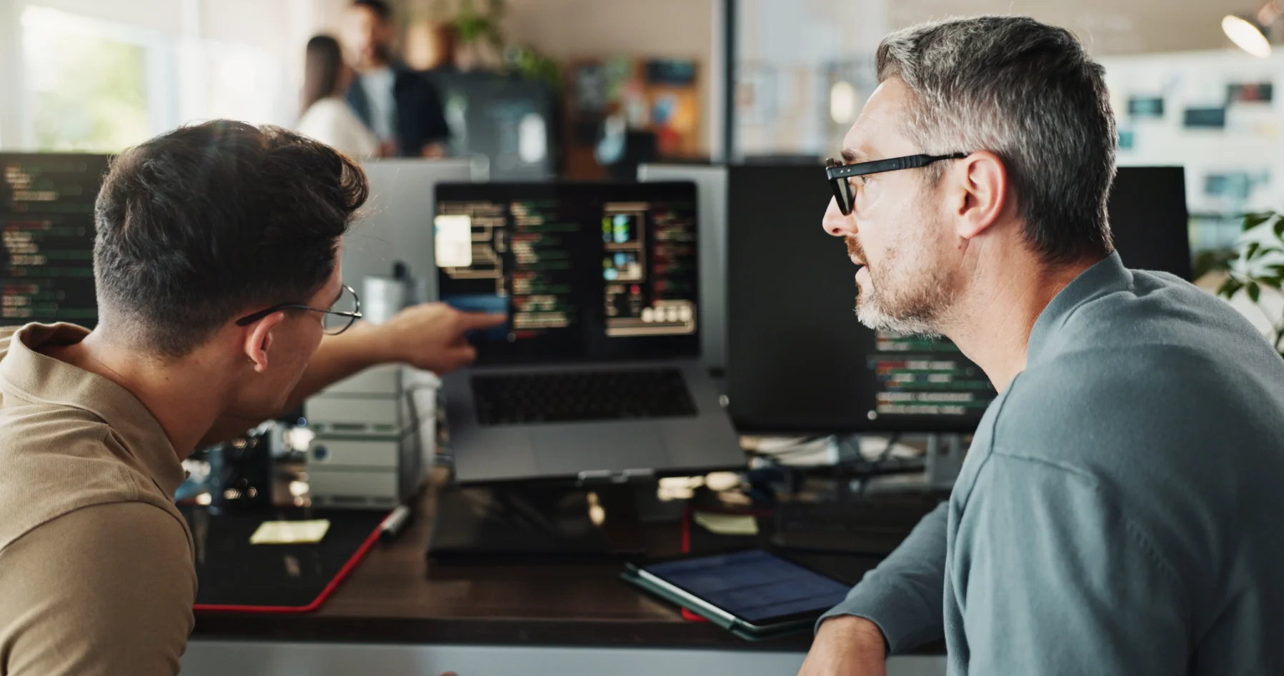 Two colleagues reviewing software code together at a computer workstation